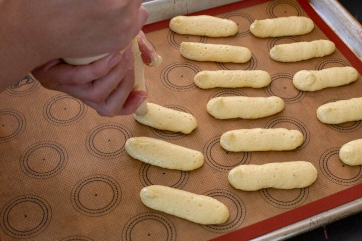 how to pipe out ladyfingers onto a sheet pan with a pastry bag