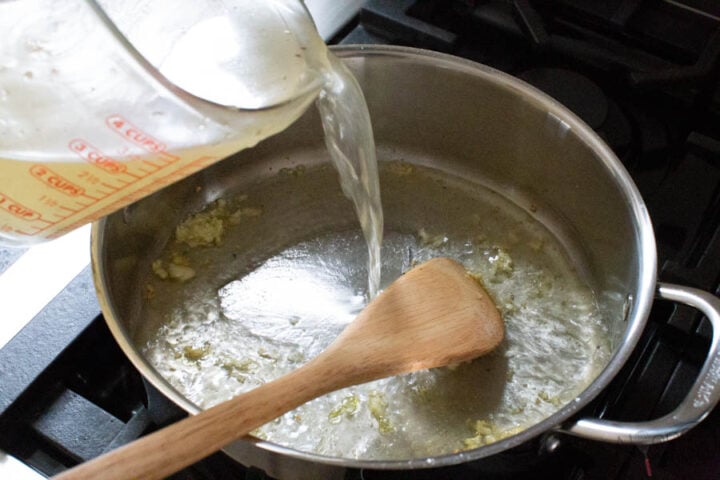 adding chicken broth to the pan for angel hair pasta