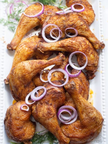chicken leg quarters with sliced purple onions and dill