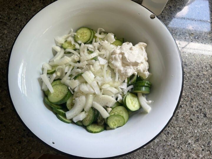 cucumbers and onion in a mixing bowl for creamy cucumber salad