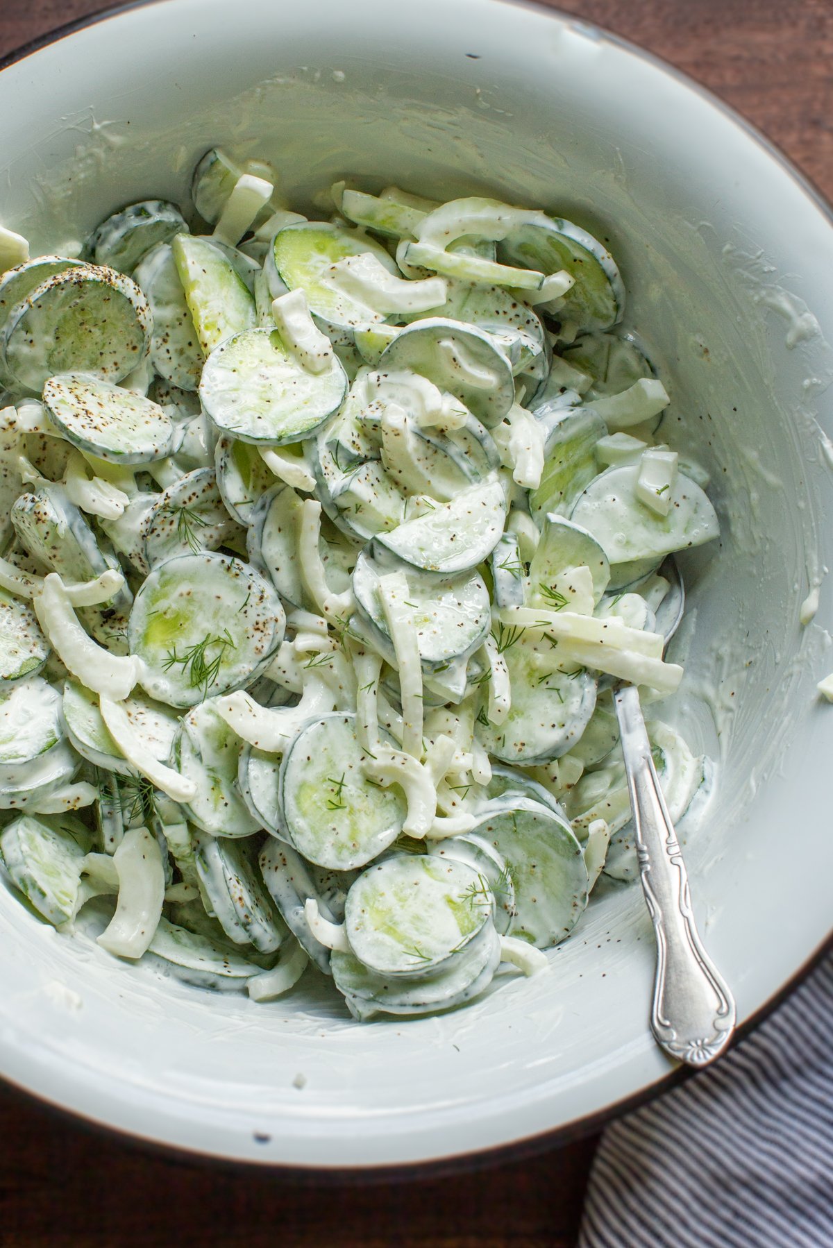 cucumber onion salad in a white enamal bowl