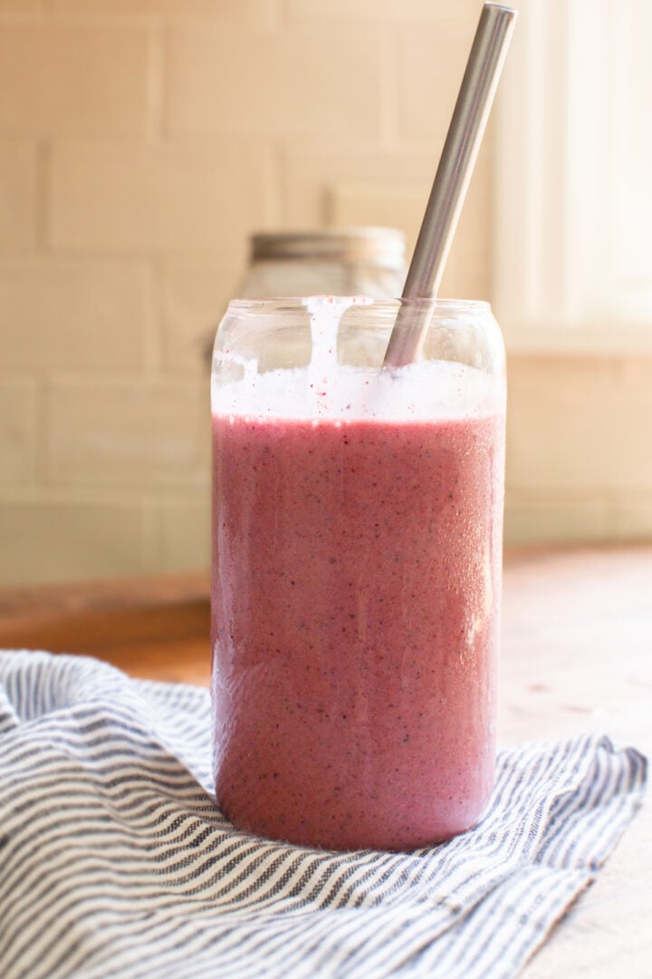 strawberry and blueberry kefir smoothie in a glass cup and metal straw