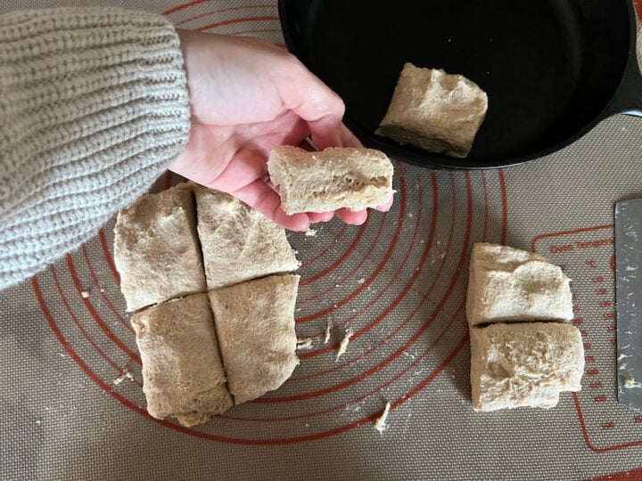 cutting square biscuits and arranging in cast-iron pan