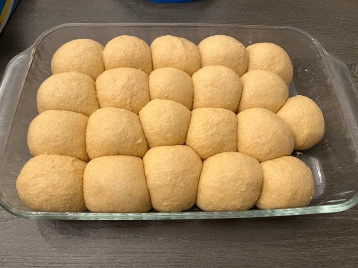risen sourdough dinner rolls in a pan before baking