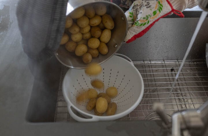 draining whole boiled potatoes into a colander