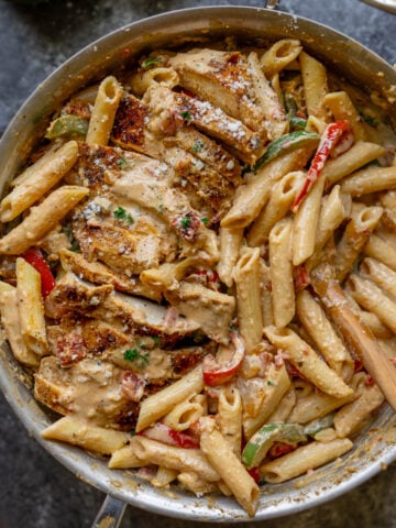 creamy cajun chicken pasta in a skillet with bell peppers and onion