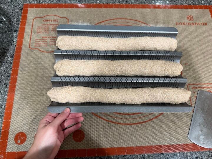 three sourdough baguettes on a baguette pan ready to be put into the fridge over night