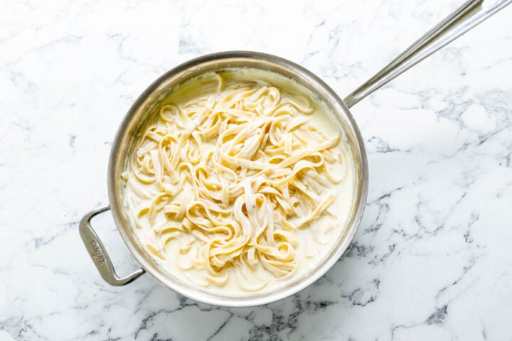 Adding the cooked fettuccine pasta to the homemade Olive Garden Alfredo Sauce