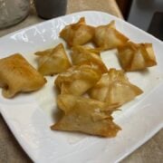 Crab ragoons on a white plate.