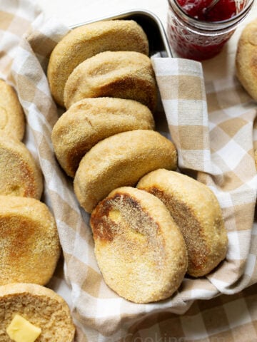 Whole Wheat English muffins arranged on a farmhouse kitchen towel in a bread pan