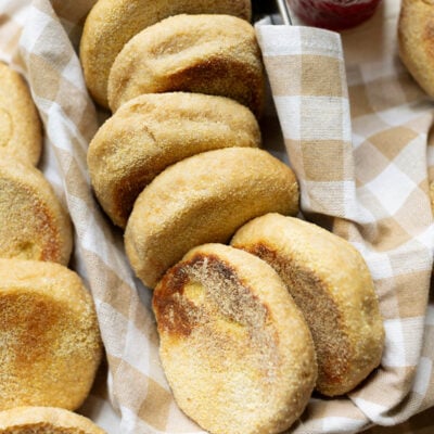 Whole Wheat English muffins arranged on a farmhouse kitchen towel in a bread pan
