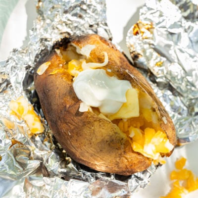 image of baked potatoes cooked from the fire (unwrapped from foil and topped with butter, cheese, and sour cream)