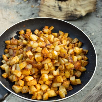 image of campfire breakfast potatoes on a skillet near a hot fire