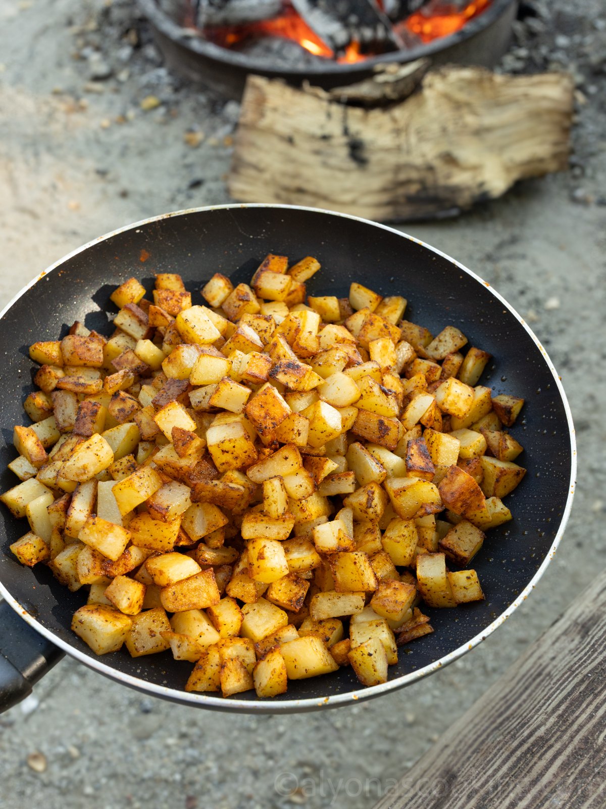 image of campfire breakfast potatoes on a skillet near a hot fire 