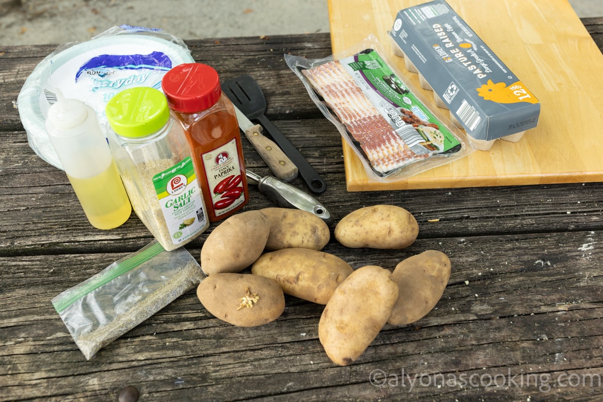 All ingredients for campfire breakfast potatoes (russet potatoes, garlic salt, paprika, black pepper, cooking oil). Bacon and eggs are optional