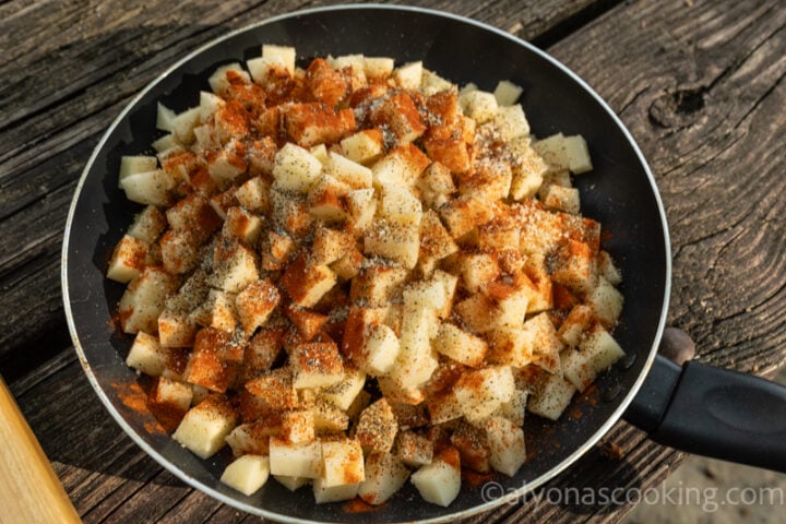 image of breakfast potatoes seasoned with paprika, garlic salt, and black pepper on a skillet outdoors