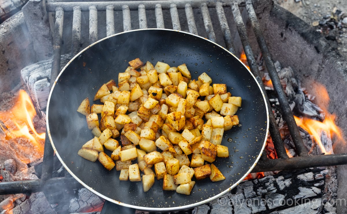 Image of how to cook breakfast potatoes on a skillet over a fire