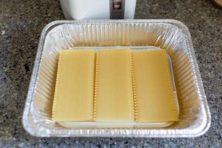 image of uncooked lasagna noodles in a pan about to be soaking in boiling water