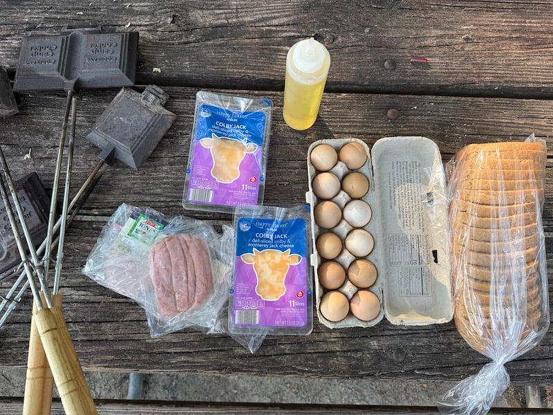 image of all mountain pie ingredients (whole wheat bread, eggs, ham, cheese, cooking oil, mountain pie makers)