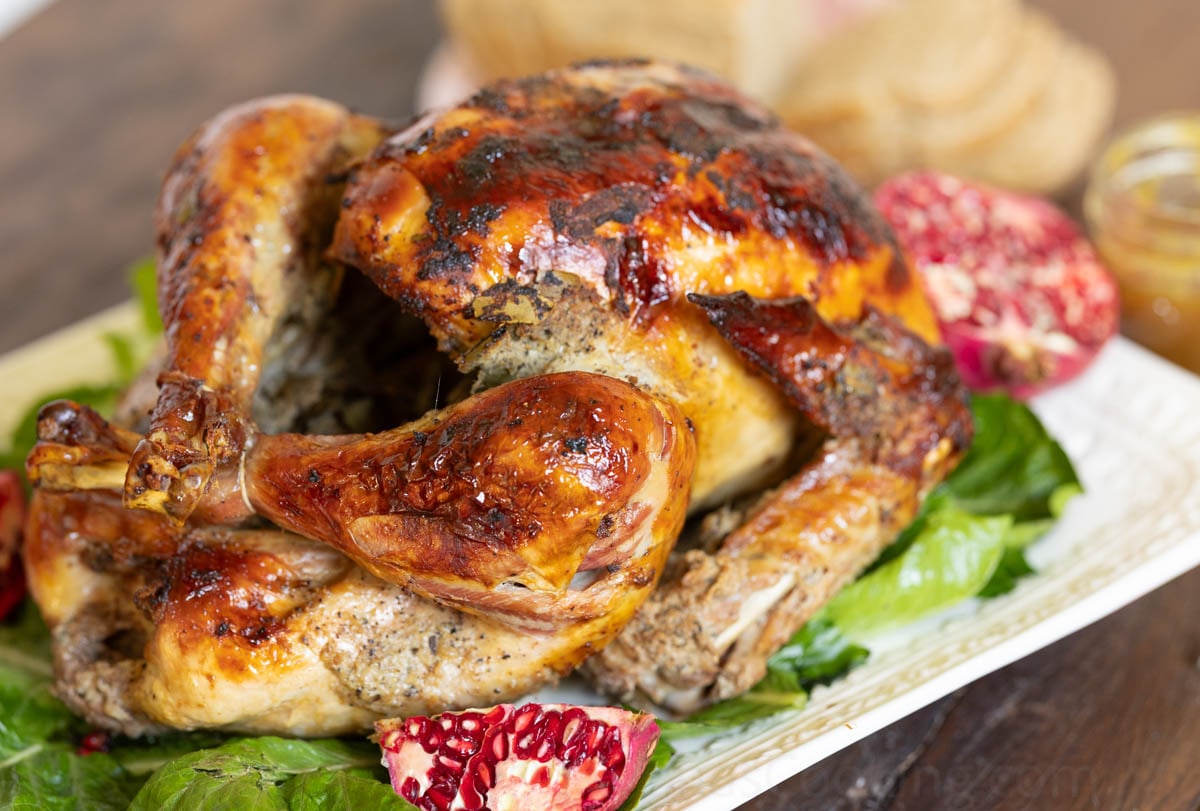 image of a juicy Thanksgiving turkey on a serving platter with lettuce and pomegranates