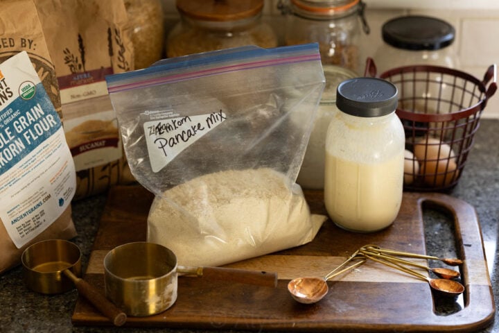 image of a homemade einkorn pancake mix on a rustic cutting board with vintage baking tools and farm fresh eggs in the back ground