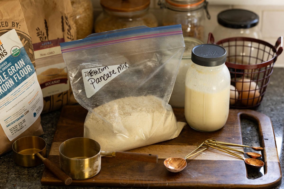 image of a homemade einkorn pancake mix on a rustic cutting board with vintage baking tools and farm fresh eggs in the back ground