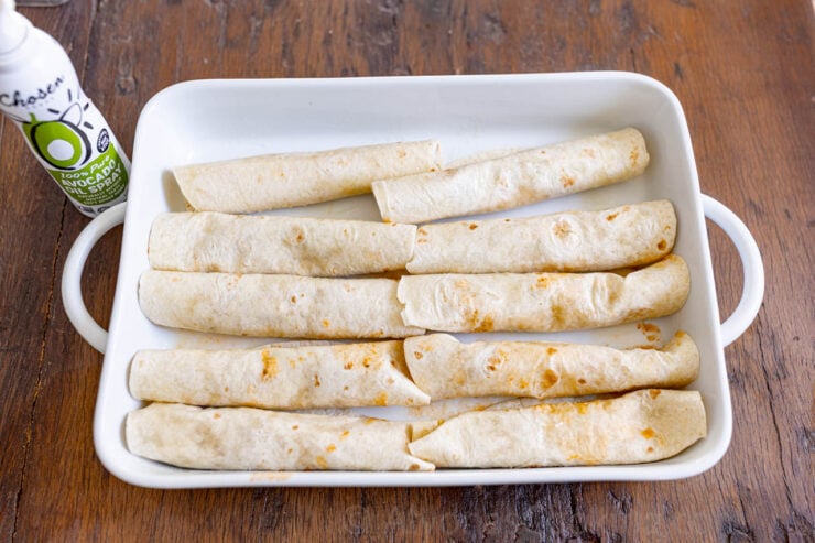 image of greased and arranged chicken enchiladas in a casserole dish