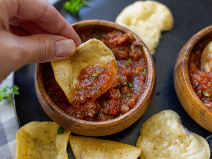 image of homemade salsa made from canned tomatoes in a serving bowl with a hand held tortilla chip