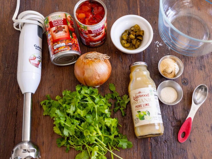 image of all the ingredients for salsa made with canned tomatoes (fire roasted diced tomatoes, pickled jalapeños, spices, sugar, onion, and cilantro).