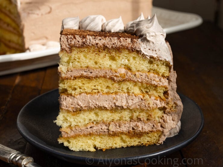 image of a sliced tiramisu cake that is layered with sponge cake layers and a chocolate whipped frosting