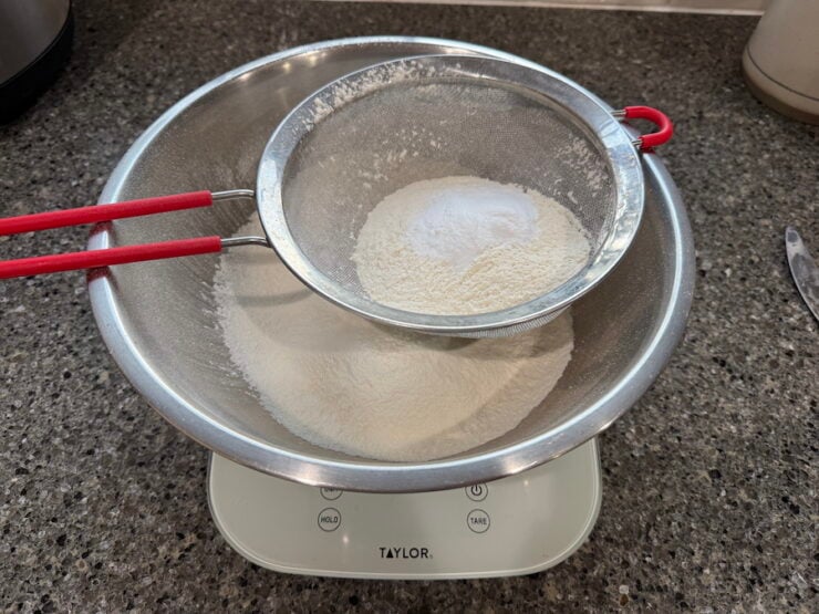 image of sifted all-purpose flour and baking soda over a sieve for tiramisu cake