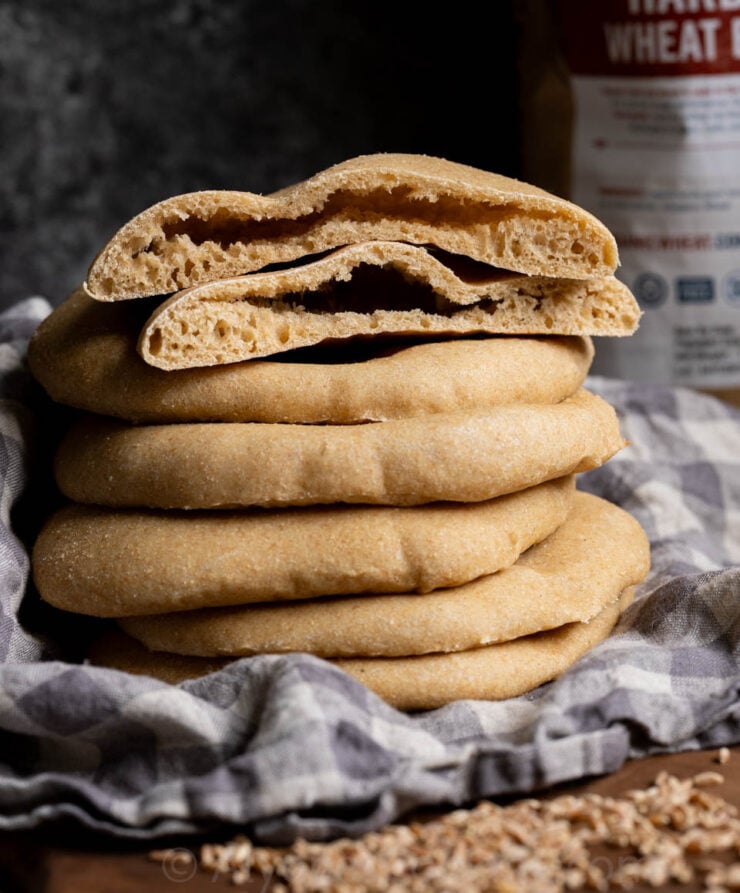 image of sourdough whole wheat pita pockets stacked on a linen gingham towel
