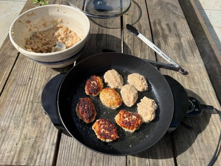 image of chicken Kotleti fried in an electric skillet outdoors.