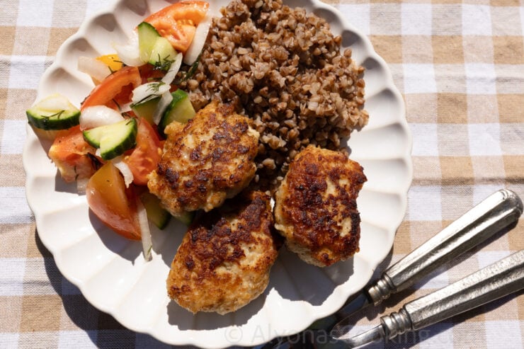 chicken Kotleti on a plate with buckwheat and a fresh cucumber and tomato salad