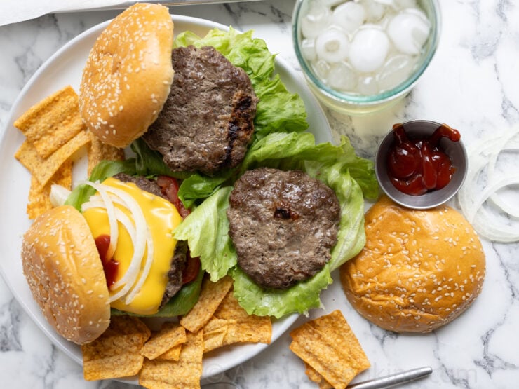 image of homemade sheet pan burgers assembled on a plate with all the burger toppings