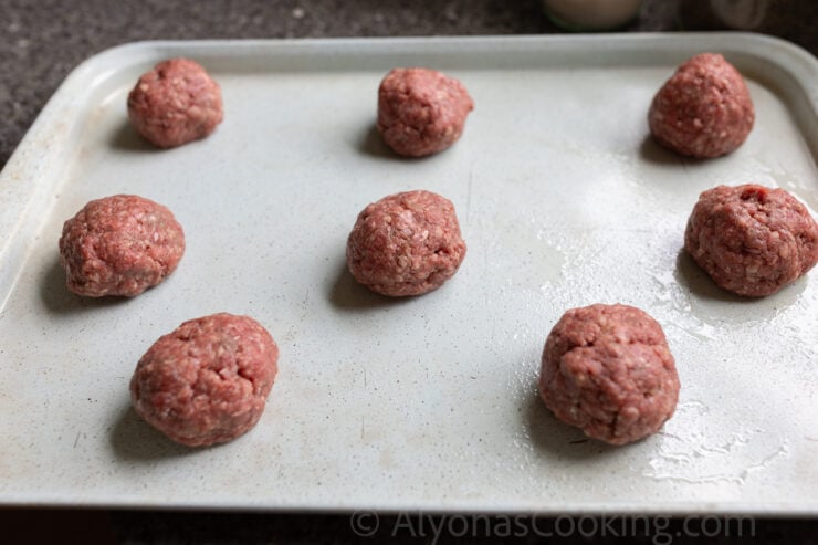 image of hamburger patties shaped into balls before flattening on a greased sheet pan.