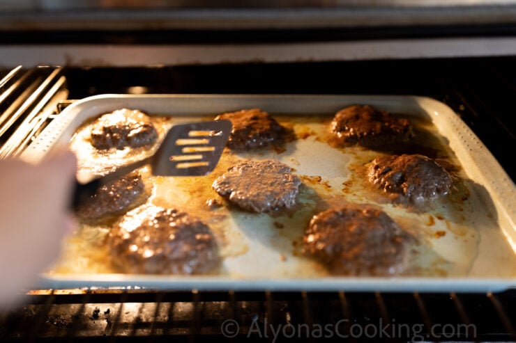 image of oven baked hamburger patties being flipped over with a spatula