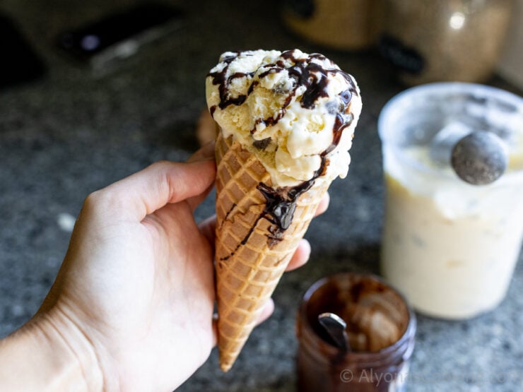 image of homemade mint chocolate chip ice cream scooped into a waffle cone drizzled with homemade hot fudge sauce
