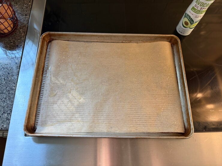 preparing the sheet pan by lining it with parchment paper and greasing it
