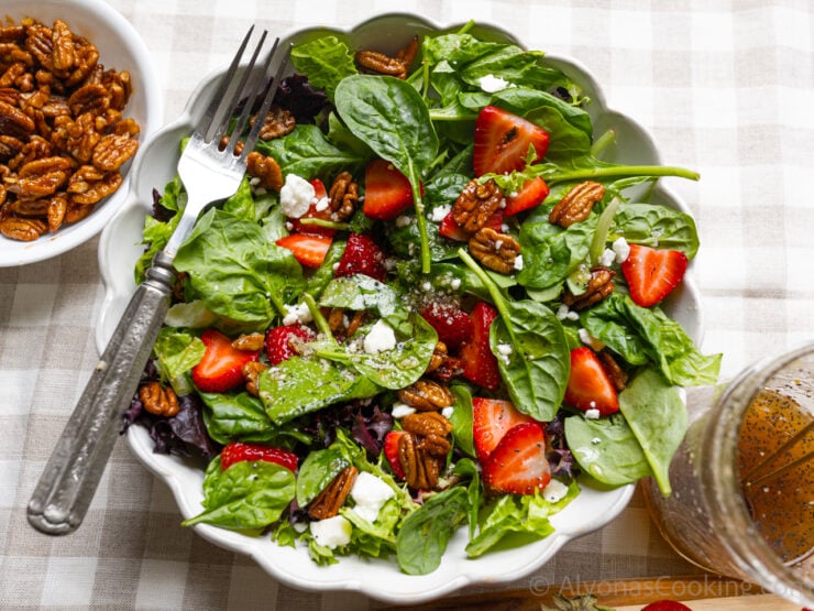 strawberry spinach salad photographed with maple candied pecans, and homemade poppy seed dressing.