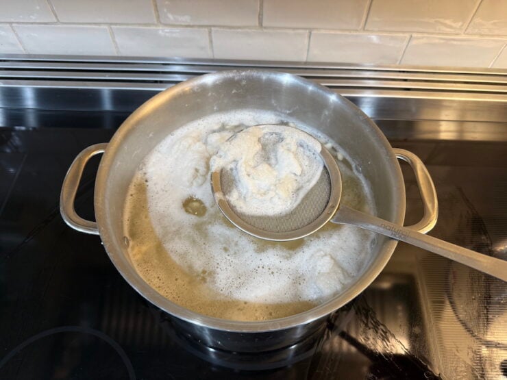 image of foam being skimmed from the pot of boiled navy beans for home-canned baked beans