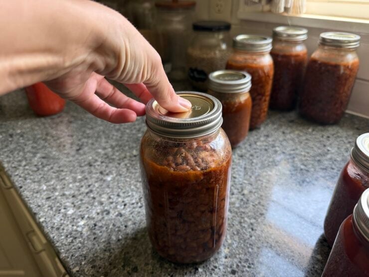 image of Alyona checking the lids of home-canned baked beans