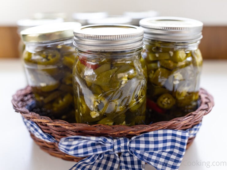 image of home canned pickled jalapeños in a woven basket with a gingham ribbon