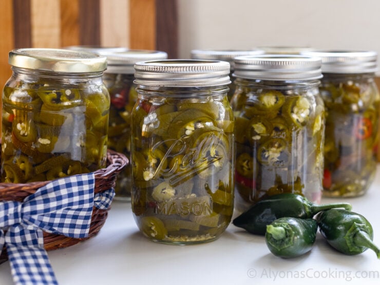 image of home canned pickled jalapeños in pint jars with fresh jalapeños