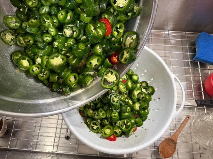 image of sliced fresh jalapeños drained in a colander from salt water