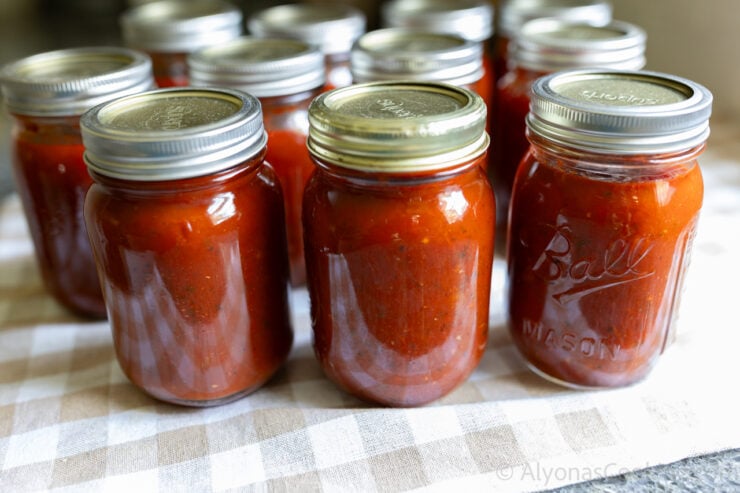 batch of home canned pizza sauce on a gingham kitchen towel